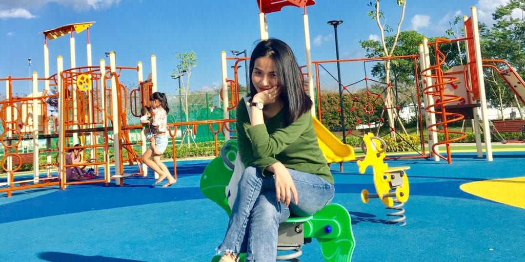 Woman Sitting on a Spring Rider Smiling on a Playground