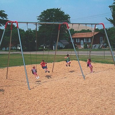 Kids swinging on a swingset in a park with wood mulch